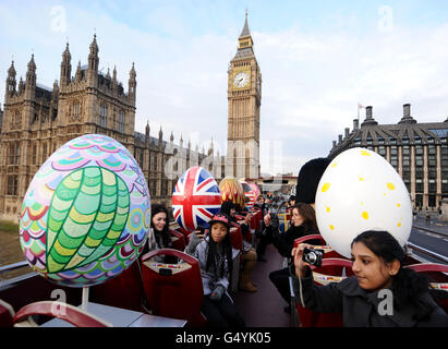 Giant decorated eggs, which will form part of the Faberge Big Egg Hunt, are driven past the Houses of Parliament, in central London, on an open-top tour bus. Stock Photo