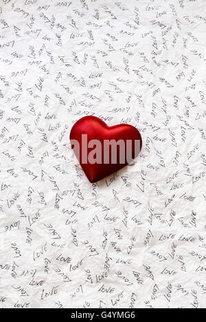 Hand made red heart on white tissue paper on which has been written in black ink the word Love. Stock Photo