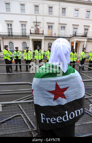 A woman wrapped in a Syrian flag as protesters outside the Syrian Embassy in Belgrave Square in central London, demonstrate about the escalating conflict in Syria. Stock Photo