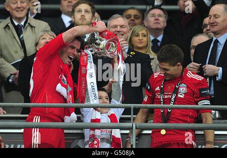 Liverpool's Jamie Carragher (left) and his son celebrate with the Carling Cup Trophy as Steven Gerrard (right) looks on Stock Photo