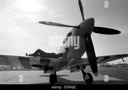 Jim Kennedy finds a suitable place to catch the sun on the wing of this vintage Spitfire. The World War Two aircraft is one of many on display at the Biggin Hill International Air Fair Stock Photo