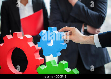 Business people assembling cogwheels, teamwork concept Stock Photo