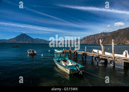 Blue skies over Lago de Atitlan and San Pedro Volcano, Guatemala where boats are moored at the docks on the lakeshore of the harbour town Panajachel Stock Photo