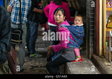 China, Yunnan Sheng, Lijiang Shi, Old Town of Lijang, Chinese mother with her little child on his back Stock Photo