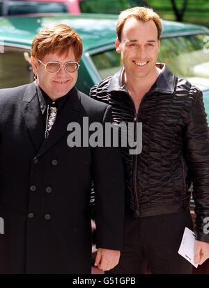 Musican Sir Elton John (L) and partner David Furnish arrive at the Ivor Novello Award ceremony in London. Sir Elton was rewarded for his contribution to The Lion King stage show, which took an award for international achievement in musical theatre. Stock Photo