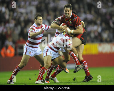 Warrington Wolves' Trent Waterhouse is tackled by Wigan Warriors' Thomas Leuluai (bottom)during the Stobart Super League match at the DW Stadium, Wigan. Stock Photo