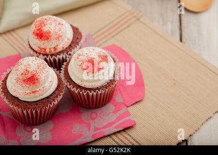 Three red velvet cupcakes on colorful paper bag Stock Photo