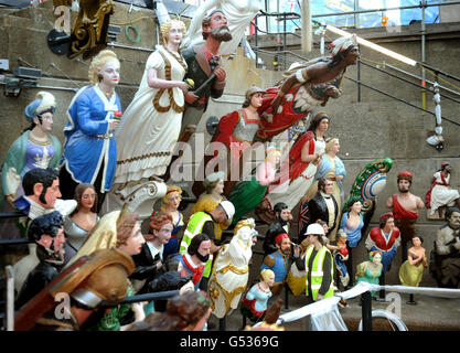 Conservators work in the dry berth under the Cutty Sark in Greenwich, London, as they apply the finishing touches to a display of over 80 figureheads. Stock Photo