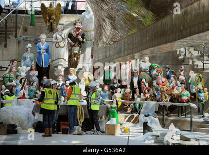 Conservators work in the dry berth under the Cutty Sark in Greenwich, London, as they apply the finishing touches to a display of over 80 figureheads. Stock Photo