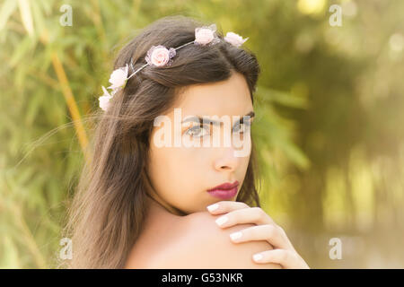 Beautiful woman wearing floral headband hand touching shoulder outdoors Stock Photo