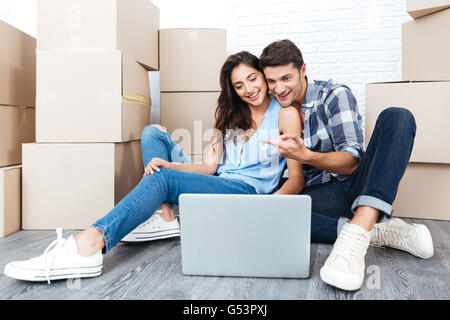 Smiling couple ready to move out looking for a new apartment on their laptop Stock Photo