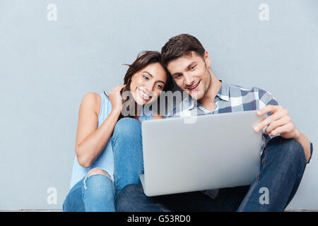 Portrait of happy young couple using laptop isolated on gray background Stock Photo