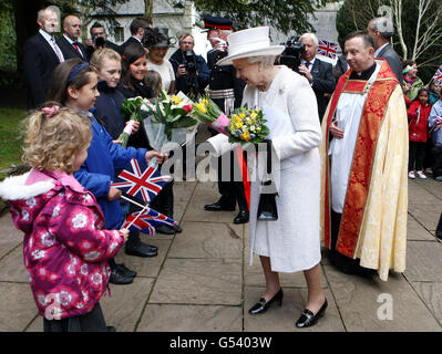 Queen Elizabeth II receives flowers from 9-year-old Georgie Seager as she leaves Llandaff Cathedral, Cardiff, during a visit to Wales as part of a UK-wide tour to celebrate her Diamond Jubilee. Stock Photo