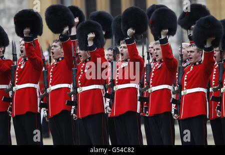 Members of the 1st Battalion and No. 7 Company the Coldstream Guards raise their bearskins as they give three cheers for the Queen Elizabeth II after being presented the colours at Windsor Castle. Stock Photo