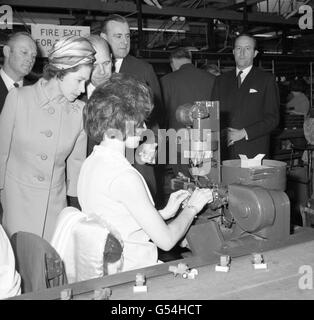 Queen Elizabeth II intently studies a process in the packing shop during her visit to the makers of the 'Matchbox' models series - Lesney Products and Company Ltd - at Hackney Wick, London. Stock Photo