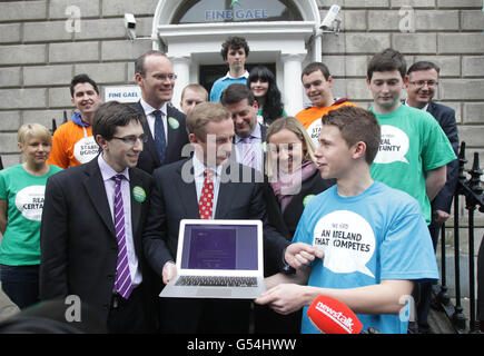 Taoiseach Enda Kenny (centre) with with Fine Gael's Director of Elections, Simon Coveney (second left) and Simon Harris TD (left), speaking to the media at the launch of an interactive element to Fine Gaels Facebook page, as part of the party's Yes campaign for the Stability Treaty Referendum, at Fine Gael head office in Dublin. Stock Photo
