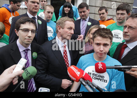 Taoiseach Enda Kenny (centre) with with Fine Gael's Director of Elections, Simon Coveney (second left) and Simon Harris TD (left), speaking to the media at the launch of an interactive element to Fine Gael's Facebook page, as part of the party's Yes campaign for the Stability Treaty Referendum, at Fine Gael head office in Dublin. Stock Photo