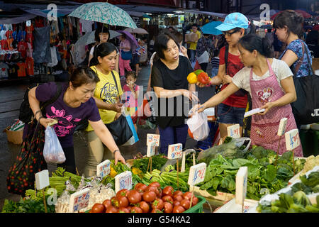 Customers buying vegetables at a stall on Chun Cheung Street in Northpoint, Hong Kong on May 24, 2015. Stock Photo