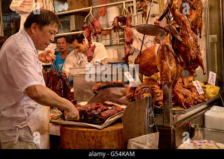 A butcher prepares some cha-siu  at a cooked foods shop on Shanghai Street in Yau Ma Tei, Hong Kong. Stock Photo