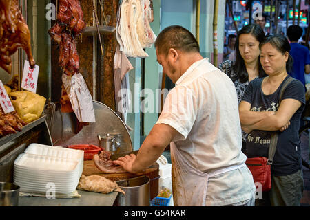 Customers queuing and buying up selections of take away cooked food at a shop on Shanghai Street in Yau Ma Tei, Hong Kong. Stock Photo