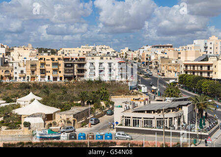 City Marsascala on the island Malta. Residential houses and a road with cars. Many clouds on the blue sky. Stock Photo