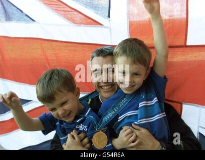 Triple Jump Olympic Gold medalist Jonathan Edwards shows off his medal with sons Nathan, five (left) and Samuel, seven, at the Gateshead Stadium Stock Photo