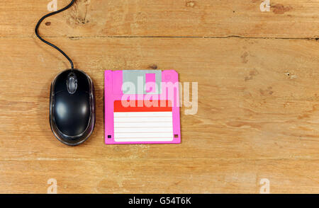 Black wired computer mouse and floppy disk on wood table Stock Photo