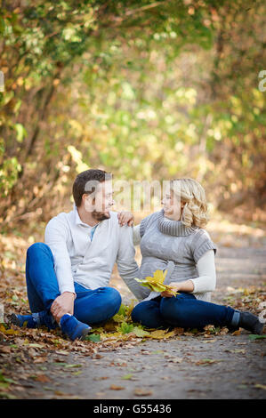 Husband and his pregnant wife relaxing in autumn park Stock Photo