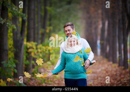 husband and pregnant wife are walking in autumn park Stock Photo