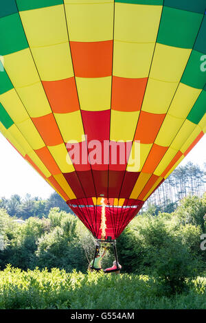 Hot air balloon taking off, inflating, during Quechee hot air balloons festival with people in basket. Stock Photo