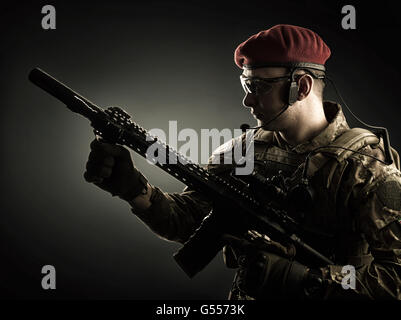 silhouette of Young handsome military man in italian camouflage holding automatic rifle, he wearing red beret and gloves Stock Photo