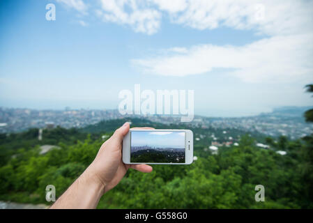 Tourist hand holding smart phone, taking photo of Batumi city, Georgia Stock Photo