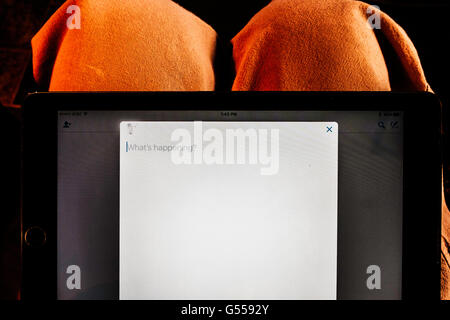 An Apple iPad Air showing Facebook's What's Happening page while set on a person's lap. Stock Photo