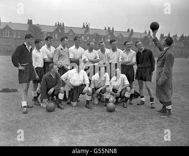 England Manager Walter Winterbottom (r) holds up a football to the Great Britain team. (top l-r) unknown. Bertie Peacock, Peter Sillett, Jack Kelsey, John Charles, Stanley Matthews, Roy Bentley, Billy Liddell, Danny Blanchflower, Don Revie and Walter Winterbottom. (ront l-r) unknown. Robert Johnston, Joseph McDonald and Jimmy McIlroy. The Great Britain team will play in a match against Europe to commemorate the Irish Football Association's 75th Anniversary in Belfast. Stock Photo