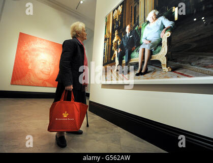 A woman views a photograph titled Queen Elizabeth II and The Duke of Edinburgh, Windsor Castle 2011 by Thomas Struth, as Elizabeth Vs Diana by Kim Dong-Yoo, a portrait of the Queen made using small portraits of Princess Diana is seen on the left, during the press preview of The Queen: Art and Image at the National Portrait Gallery, London. Stock Photo