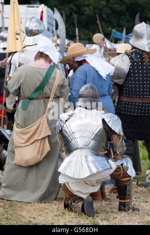 Tewkesbury, UK-July 17, 2015: Kneeling soldier in armour behind reenactors on 17 July 2015 at Tewkesbury Medieval Festival Stock Photo