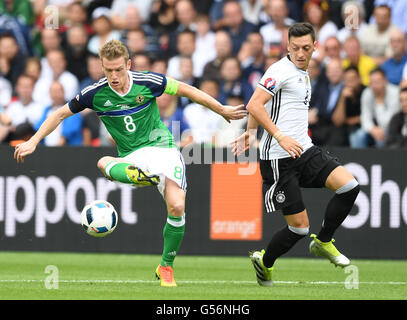 Paris, France. 21st June, 2016. Germany's Mesut Oezil and Northern Ireland's Steven Davis (l) challenge for the ball during the UEFA Euro 2016 Group C soccer match between Northern Ireland and Germany at the Parc des Princes stadium in Paris, France, 21 June 2016. Photo: Arne Dedert/dpa/Alamy Live News Stock Photo