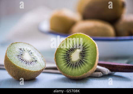 ripe vibrant kiwi fruit cut in half on wooden board, close up view Stock Photo