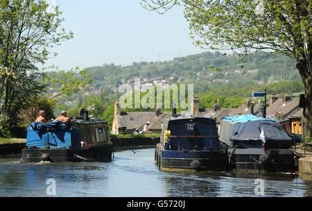 A boat makes its way along the Leeds and Liverpool Canal at Five Rise Locks, Bingley, West Yorkshire, as the warm weather continues across the UK. Stock Photo