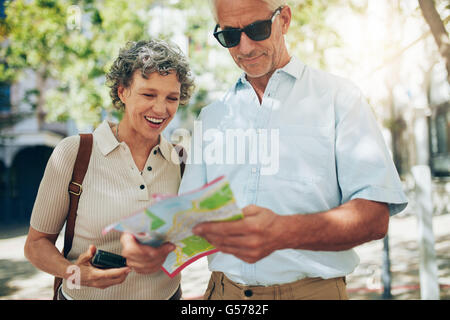 Senior couple on vacation reading a map. Mature man and woman looking for direction in foreign city. Stock Photo