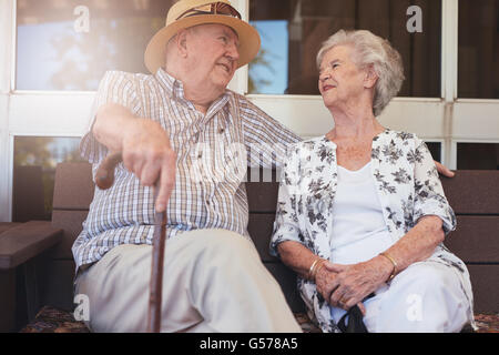 Loving senior couple relaxing on a bench outside their home. Happy retired couple having a break. Stock Photo