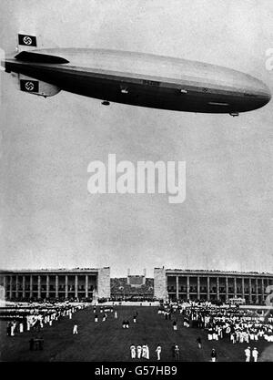 HINDENBURG: The German airship 'Hindenburg', sporting swastika flags on her tail fins, flying over the 1936 Berlin Olympic Games. On May 6th 1937 the airship exploded in a ball of fire as she came in to land in New Jersey, USA. At least 33 passengers and crew were killed. Stock Photo