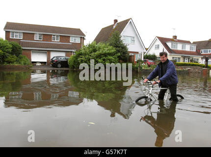 A man makes his way on a bike along a flooded road in Felpham near Bognor Regis in West Sussex, after the South East and mid Wales were worst hit by the rain which has battered Britain. Stock Photo