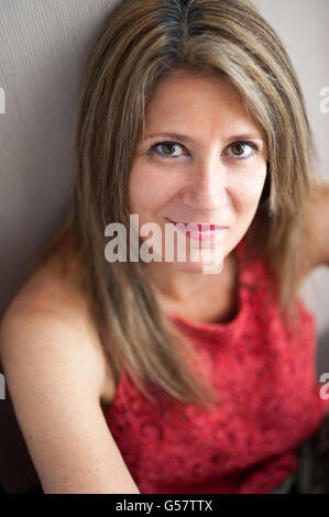 Close up Attractive Middle Aged Woman Looking at the Camera with Half Smile Face While Leaning Against the Wall. Stock Photo