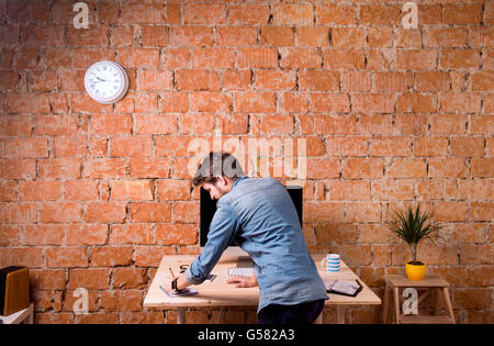 Business person standing at office desk working, rear view Stock Photo
