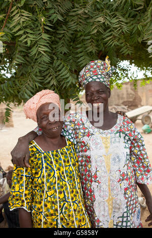 Two women stand together wearing traditional dress in Niassan Village, Burkina Faso. Stock Photo