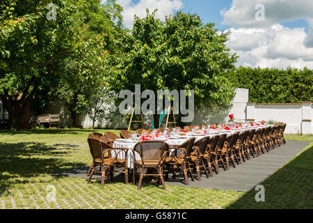 garden party set up for lunch dinner with long table , Decorated table with candles in the garden Stock Photo