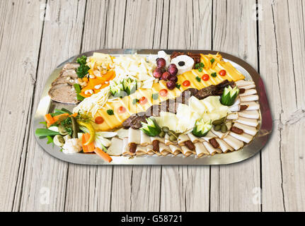 Cold plate with ham, cheese, olives, sausage, fresh fruit and vegetables on wooden table Stock Photo