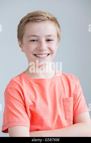 Portrait of a young boy on a plain background with his arms folded Stock Photo