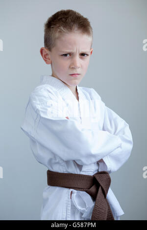 Young boy in karate clothing, posing with a tough expression on his face and his arms folded. Stock Photo